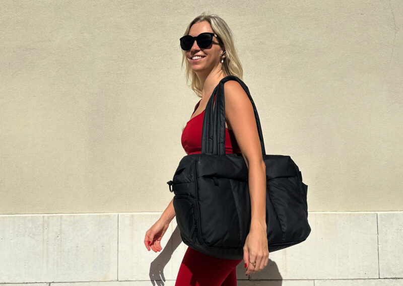 CALPAK Luka Duffel Review: Stylish and Functional Travel Bag Ally going to a workout class in a red fabletics with the calpak luka duffel 1