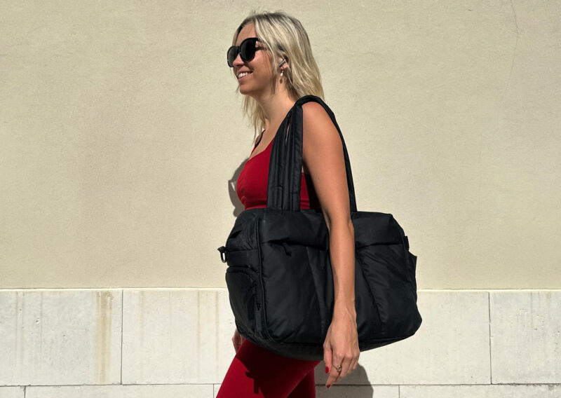 CALPAK Luka Duffel Review: Stylish and Functional Travel Bag Ally on her way to yoga in a red fable tics set with a calpak luka duffel bag