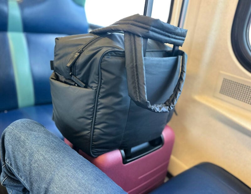 calpak luka duffel on top of quince carry-on on the LIRR - Summer 2026