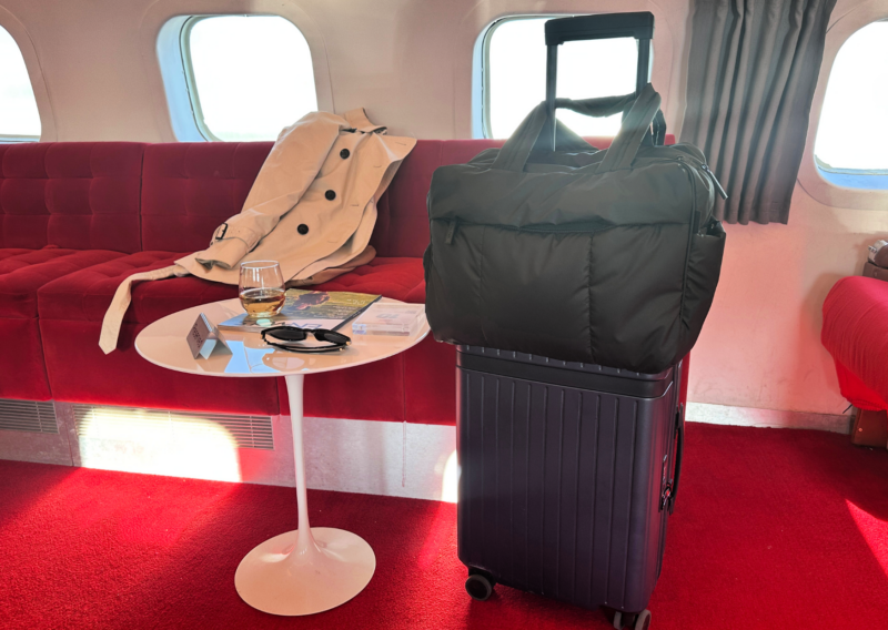 Carl Friedrik The Core Carry-On Review: Is It an Elite Bag? CARL FRIEDRICK THE CORE CARRY ON IN NAVY WITH THE CALPAK LUKA DUFFEL IN BLACK ON THE TWA HOTEL AIRPLANE BAR AT JFK AIRPORT ALL TRAVELS LUXURY TRAVEL LUXURY CARRY ONS