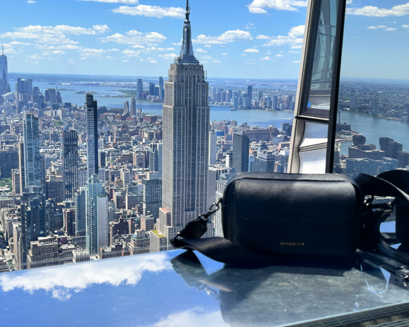 Bandolier Miller Bag Review: The Best Travel Crossbody Bag? bandolier miller bag in front of the Empire State Building at one summit observation deck with empire state building