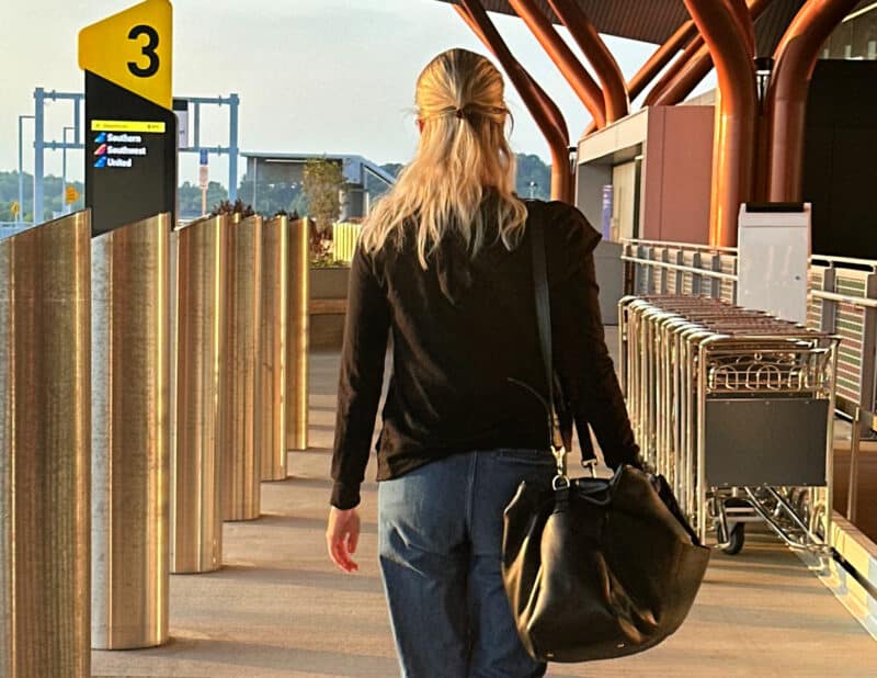 ally walking away with the quince leather weekender at the airport