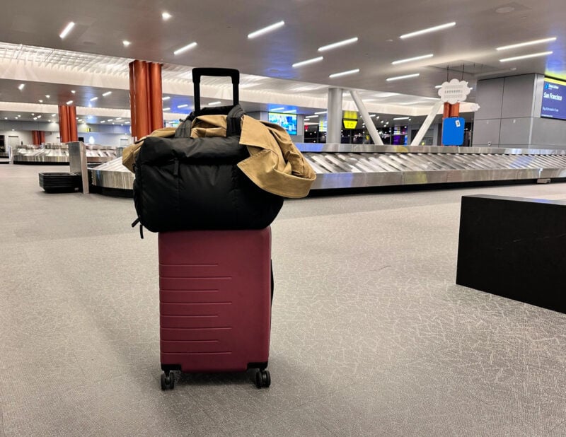 Quince Carry-On Review 2026: Worth It After 4 Real Trips? quince carry-on with the calpak luka duffel and fabletics trench inside the baggage claim area at the new Pittsburgh airport